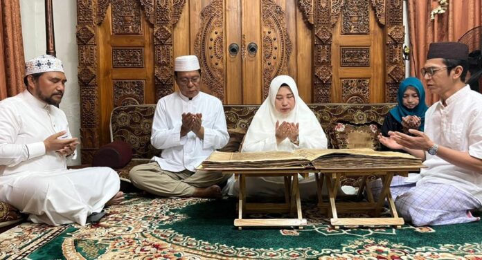 nembaca mushaf Al-Qur’an yang ditulis tangan oleh Syekh Muhammad Arsyad Al-Banjari membaca Mushaf Al-Qur’an
